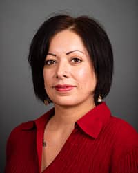 Aileen Guerra-Morales, Assistant Director for Sexual Aggression Services, Sexual Aggression Dedicated Counselor profile picture. They are wearing a red blouse with a grey background.