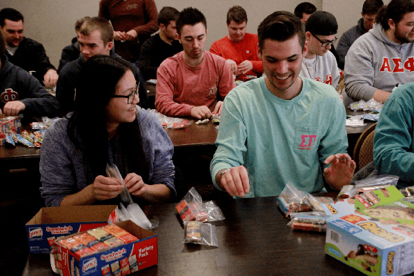 Students laughing as they pack food in plastic bags