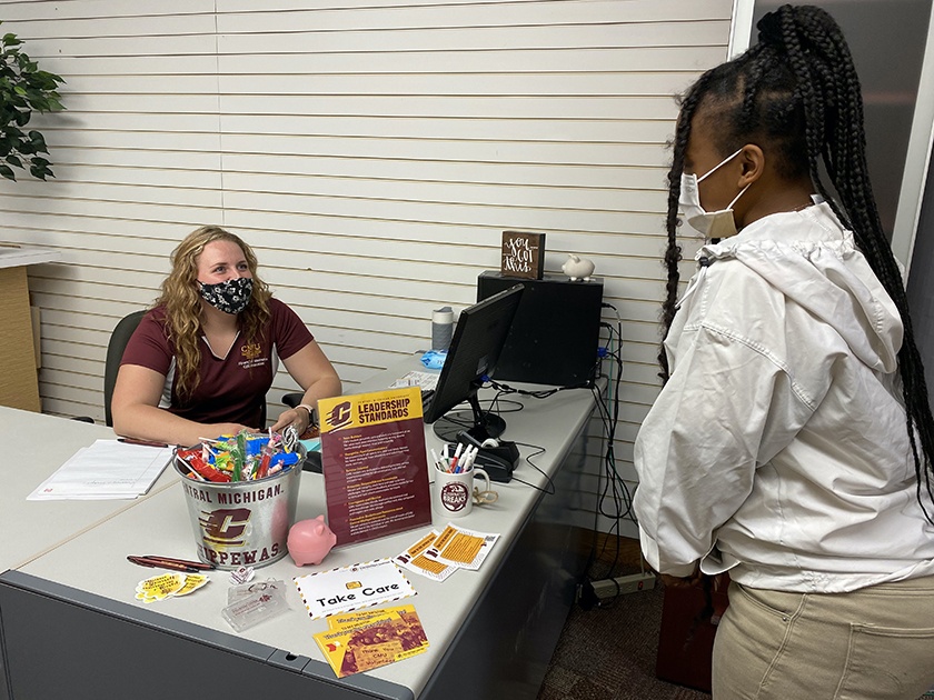 A student from the Financial Wellness Collaborative greets another student coming to the front desk.