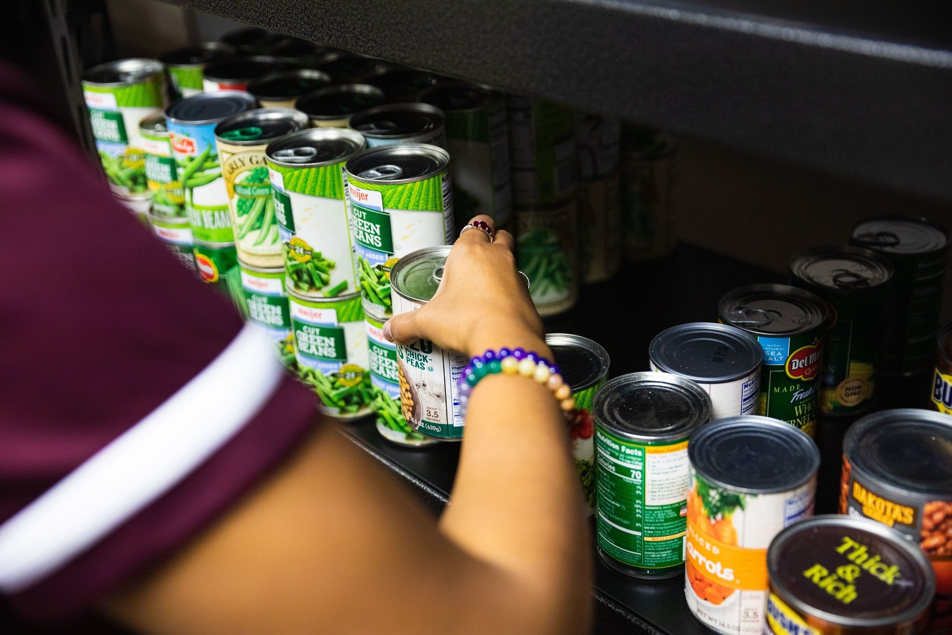 A volunteer setting up and organizing cans in the student food pantry.