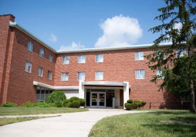 Front entrance of Beddow Hall, a red brick residence building with shrubs and a concrete path.