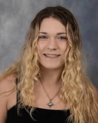 Jae Welch, Graduate Assistant for Sexual Aggression Services. Black top with long blonde hair and a grey background.