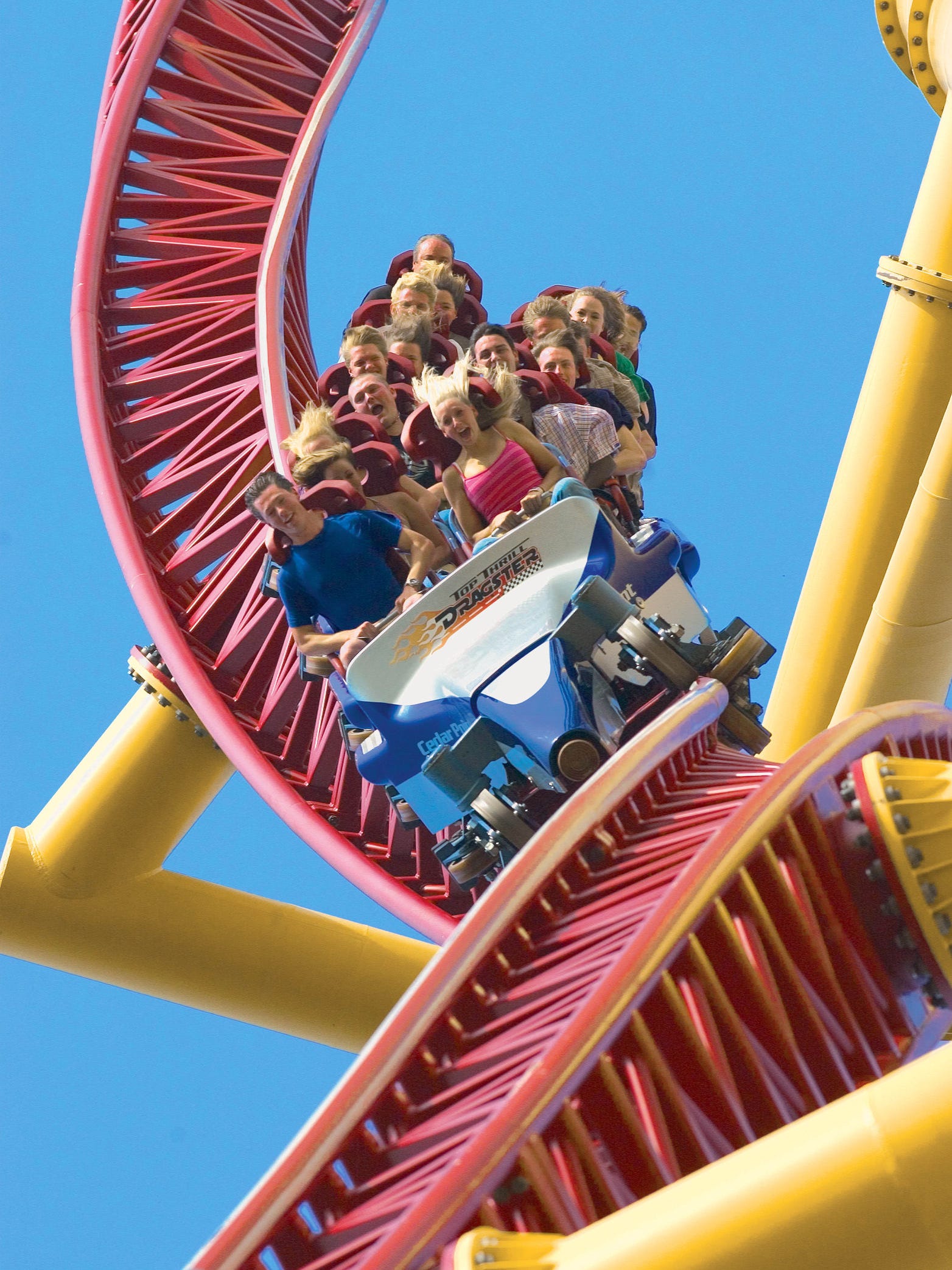 People riding a red and yellow roller coaster.