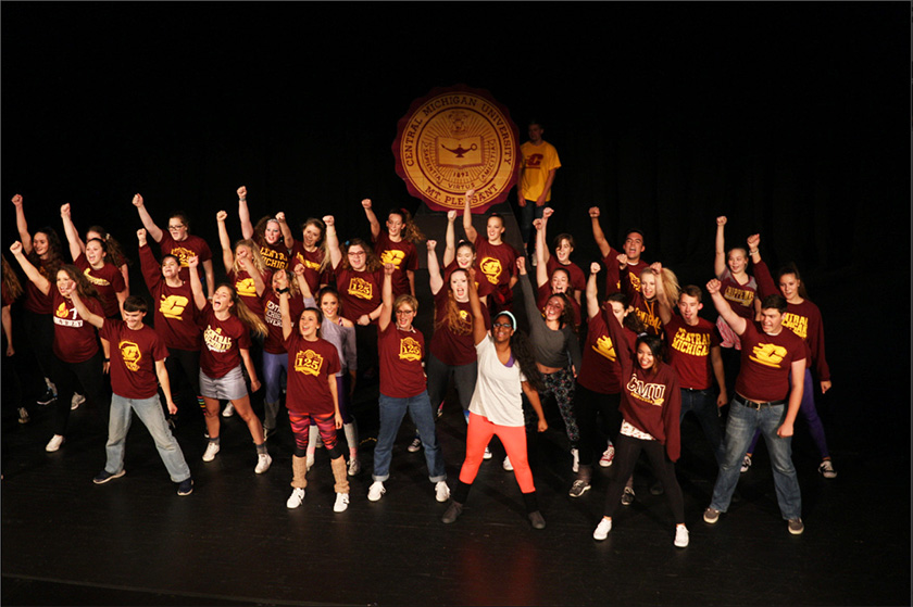 Central Michigan University students on a stage with their fists pumped in the air.