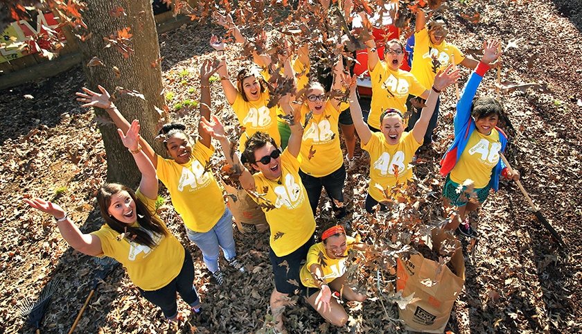 A group of Alternative Break participants throwing leaves in the air and smiling for a picture.