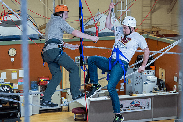 Two students participating in a high ropes activity.