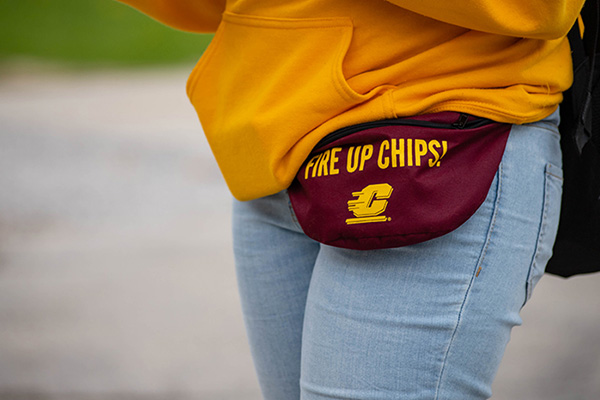 Student wearing a gold hoodie and a maroon fanny pack with the words, FIRE UP CHIPS written on it.