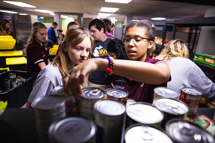 Two students looking at and sorting cans in the food pantry.