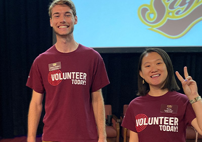 Two smiling students wearing maroon "Volunteer Today" t-shirts