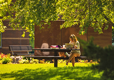 Student sitting outside at a picnic table.