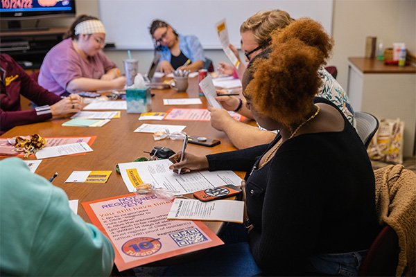 A group of students sits around a table and works through a training session.