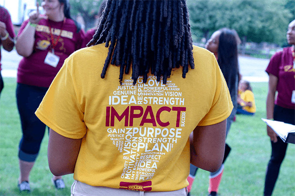 Back of a student wearing a gold IMPACT t-shirt