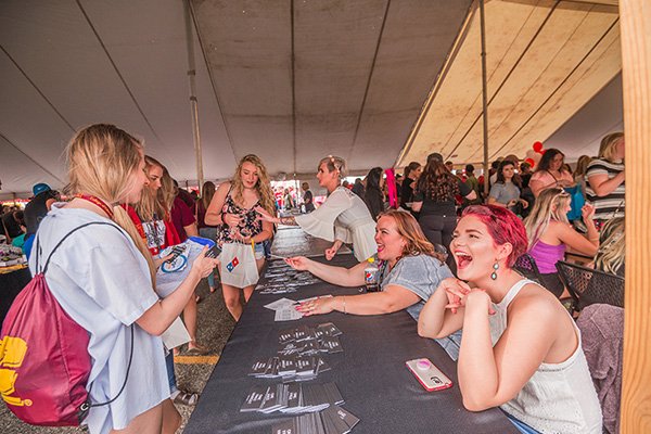 Students sitting at a table interact with other students at MAINstage event.