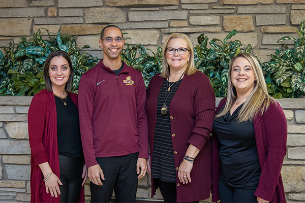 Four staff members in maroon and black clothing.