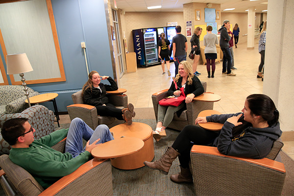 A group of students sitting and talking in the lobby of a residence hall.