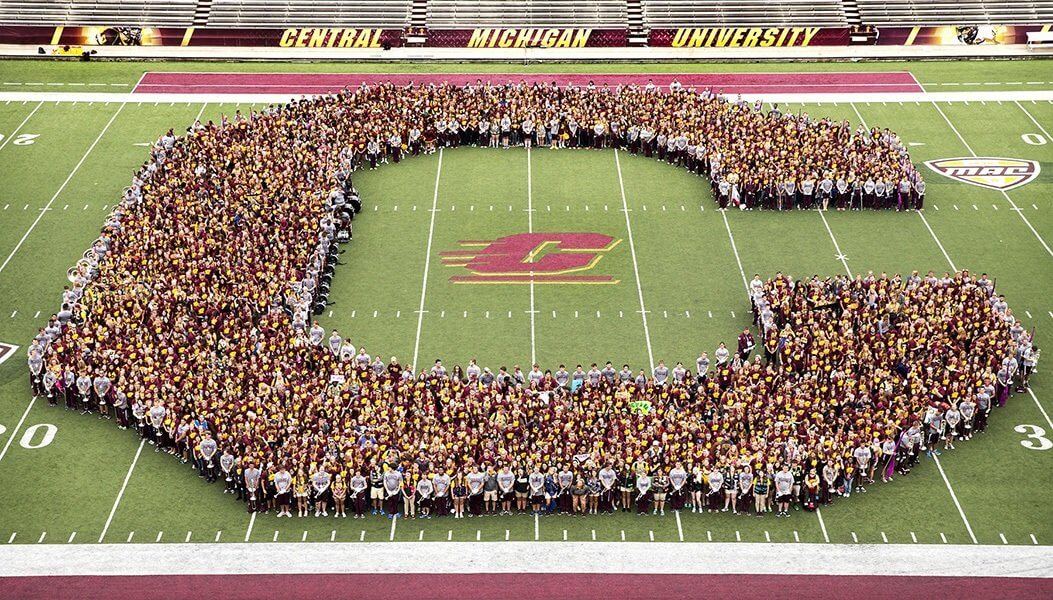 Participants of Safari standing on the football field in the shape of the action C