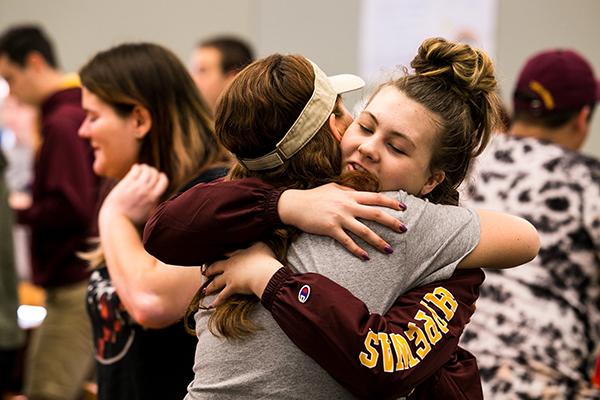 Two students in Central Michigan University clothing hug each other.