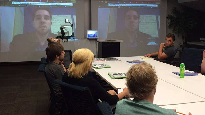 A virtual and in-person meeting taking place in a newsroom.