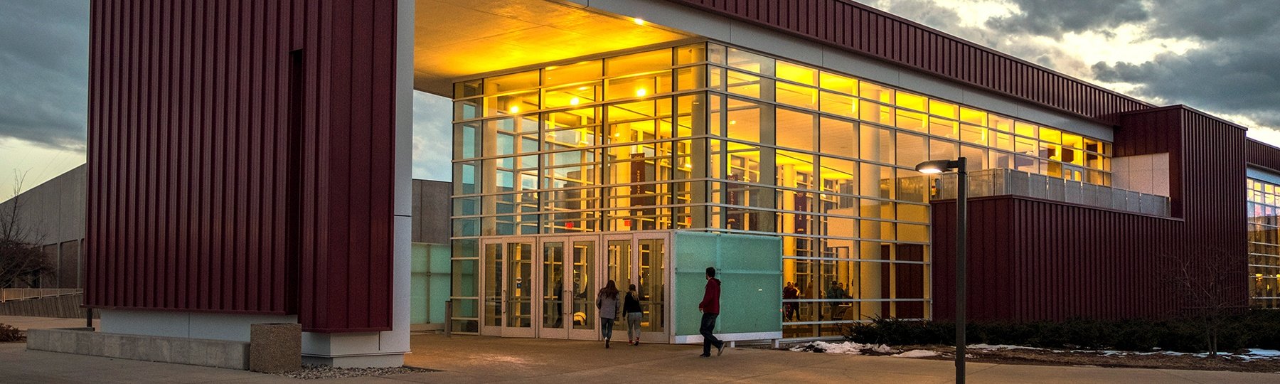Kulhavi Events Center at night with lights on inside and a cloudy sky in the background.