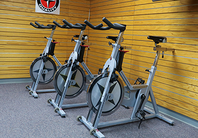 Exercise bikes in front of a wood-paneled wall.