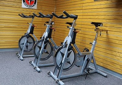 Exercise bikes in front of a wood-paneled wall.