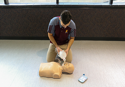 An instructor demonstrates CPR techniques on a mannequin