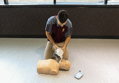 An instructor demonstrates CPR techniques on a mannequin