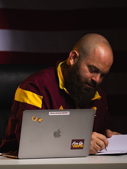 Veteran studying at a desk with the United States flag in the background.