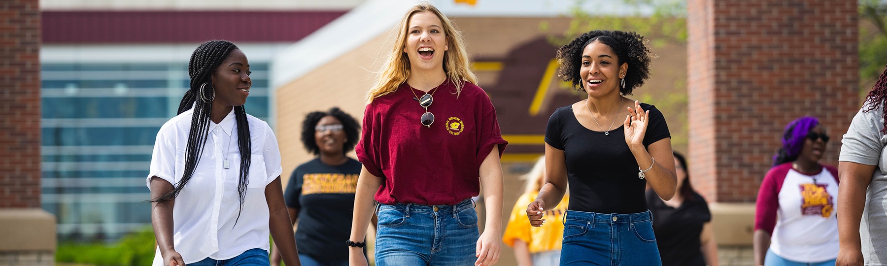 A group of female student walking and talking on campus.