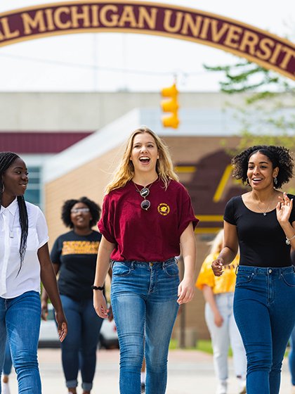 A group of female student walking and talking on campus.