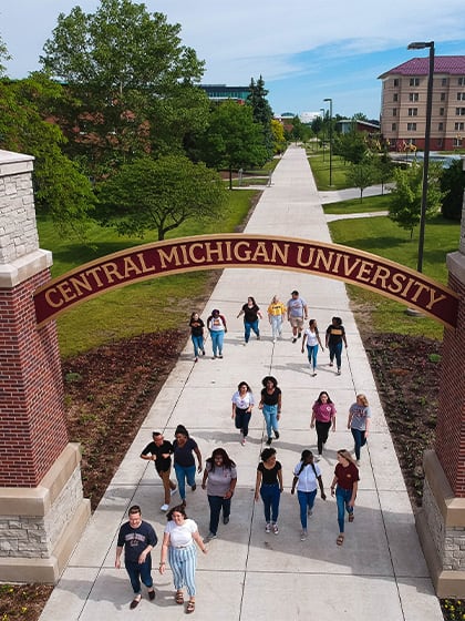 Students walking on campus under the gateway