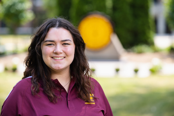 Kara Warnke, Assistant Director of Admissions, in front of the CMU Seal