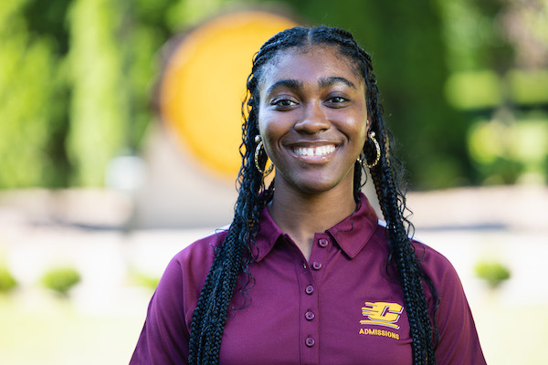 Zakia Brewer Assistant Director of Admissions in front of the CMU seal