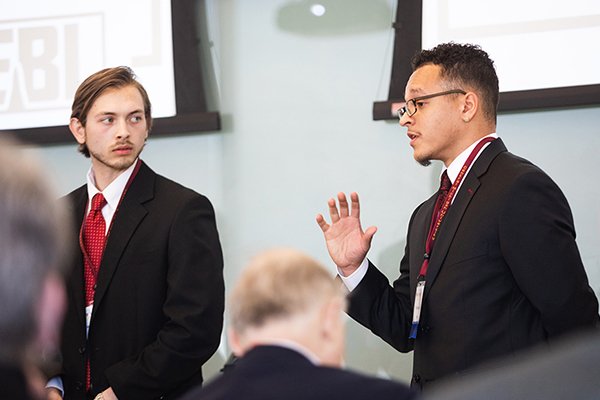 Students dressed in suits giving a seminar in front of other professionals