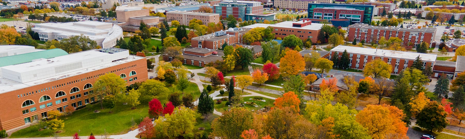 An aerial view of Central Michigan University's campus during the fall season showing the different maroons, golds and oranges of the trees.
