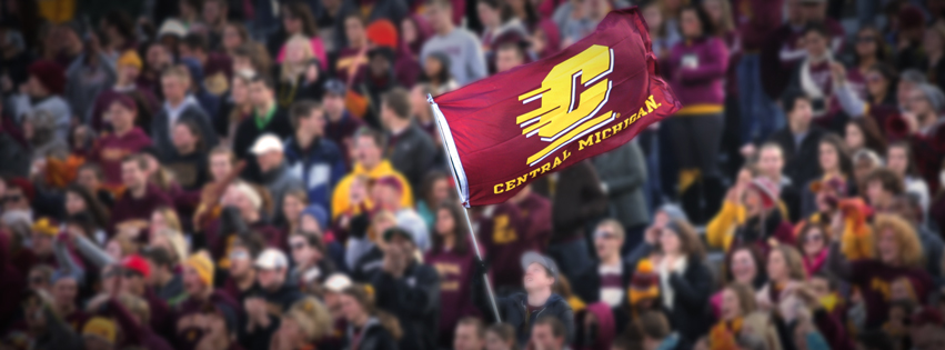 Student raising Central Michigan flag in the crowd