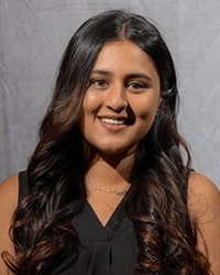 Sneha Mathew wears a black shirt and smiles for a staff photo.