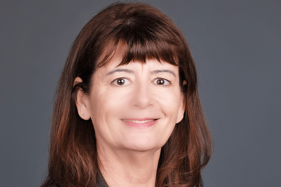 Headshot of Kelly Barton on a grey background.