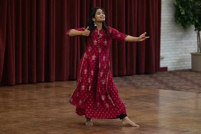 A dancer performs with one arm and foot outstretched at an Indian Dance competition
