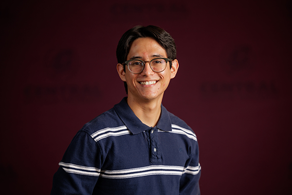 Professional headshot of Aldo Garcia-Pajaro wearing a blue and white shirt on a maroon background.
