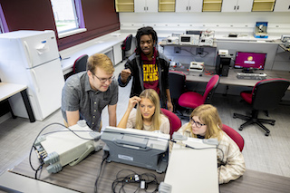 four CMU students working together in a lab