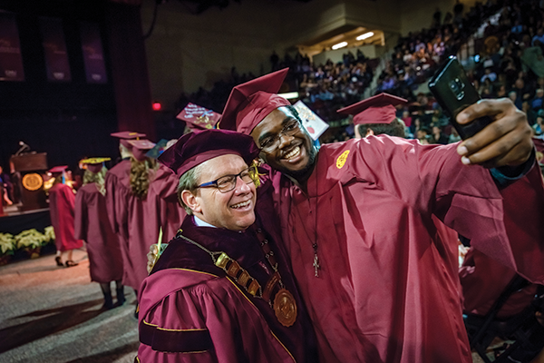 President Davies takes a selfie with a graduate at commencement