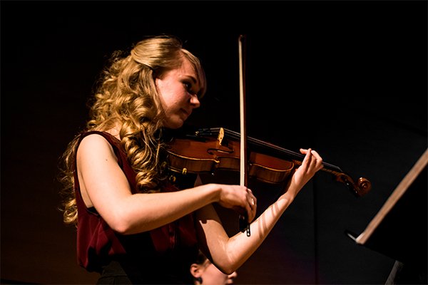 a student on a stage playing a violin