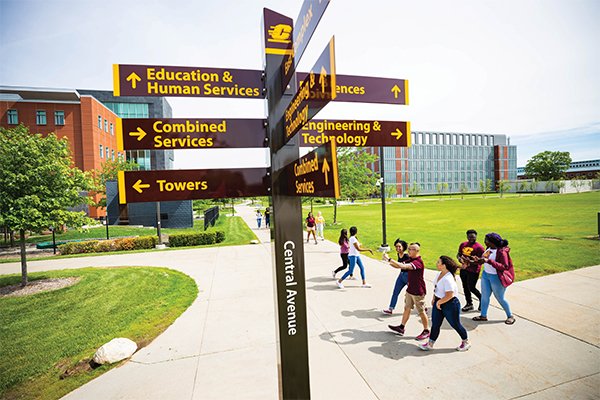 Students walking on campus near the Central Avenue sign