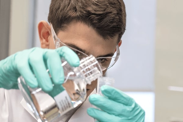 a student doing a science experiment in a white lab coat