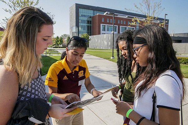 student tour guide pointing out something on map to campus visitors