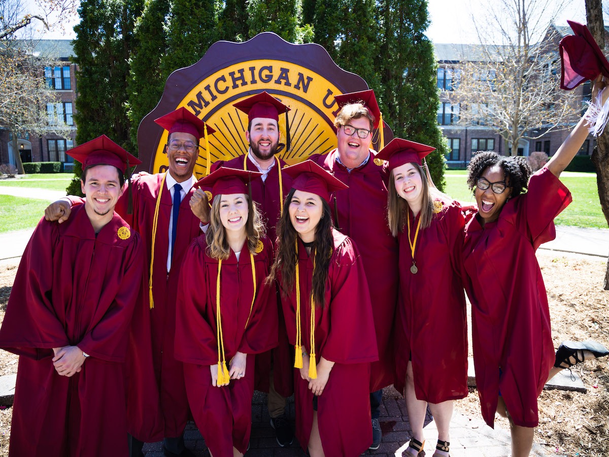 students in cap and gowns in front of CMU university seal
