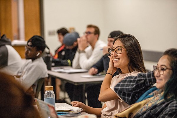 Students in class smiling or laughing facing front of the room