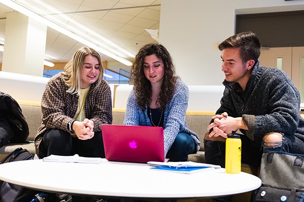 Three students sitting on a couch in front of a laptop