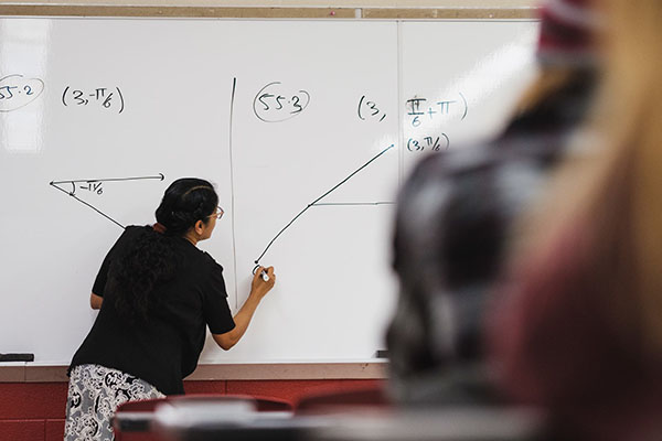 instructor doing a math problem on a white board